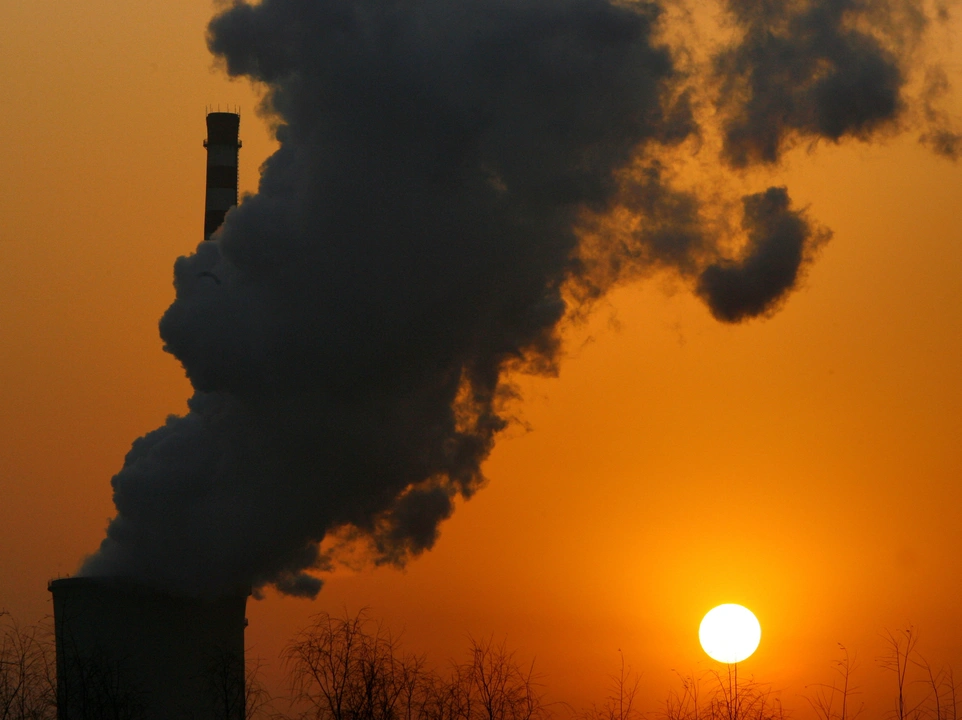 FILE PHOTO: The sun sets next to a smokestack from a coal-burning power station in Beijing January 9, 2008.  REUTERS/David Gray      (CHINA)/File Photo
